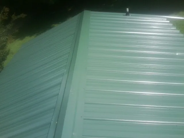 New green metal panels meeting at the ridge of a roof — Flat Roof Repair work by our crew in Lake Mary
