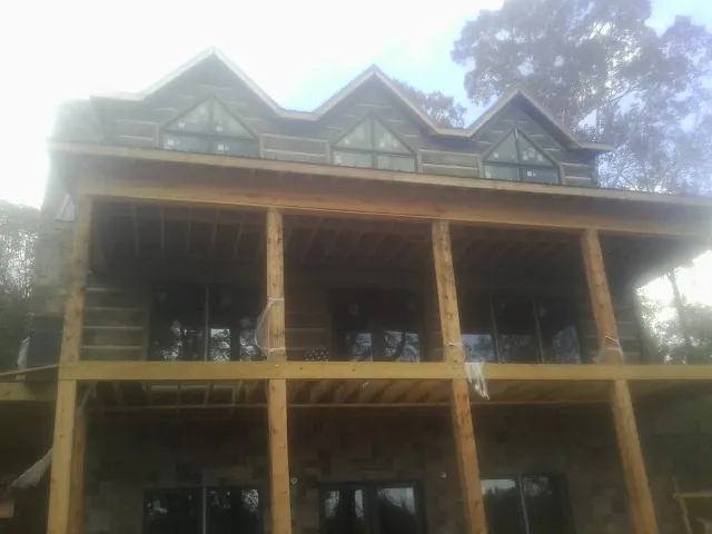 Dormers and porch framing on a large log home under construction — Roof Coating work by our crew in Lake Mary