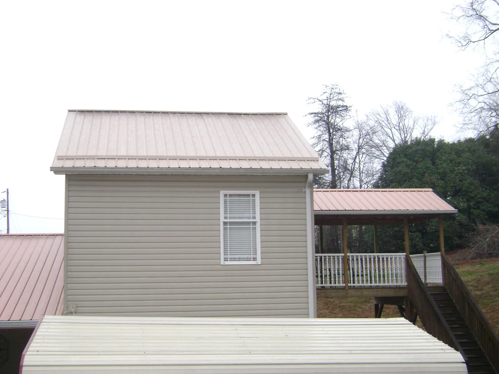Tan metal roofs on a two story addition and attached porch, from a Roof Replacement job in Lake Mary
