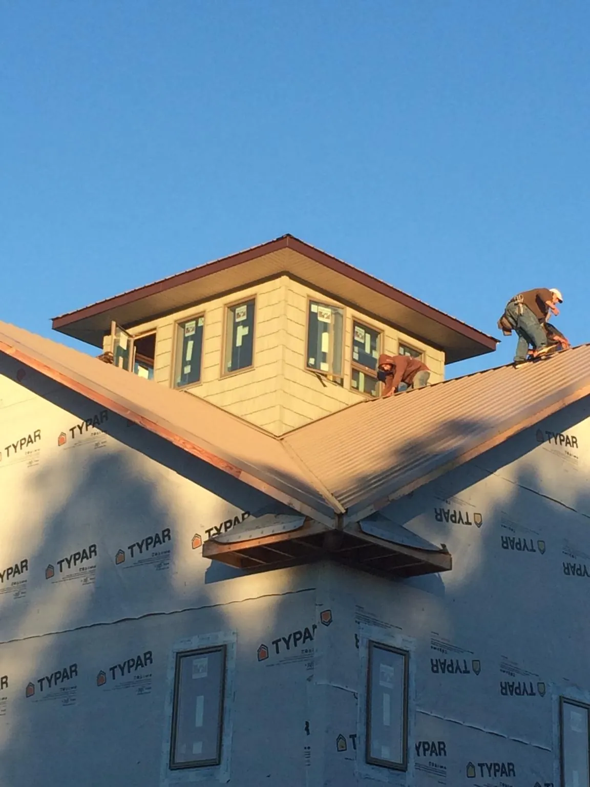 Roofers working around a rooftop cupola on a new metal roof at sunset — Roof Waterproofing in Lake Mary by Roofing Brothers
